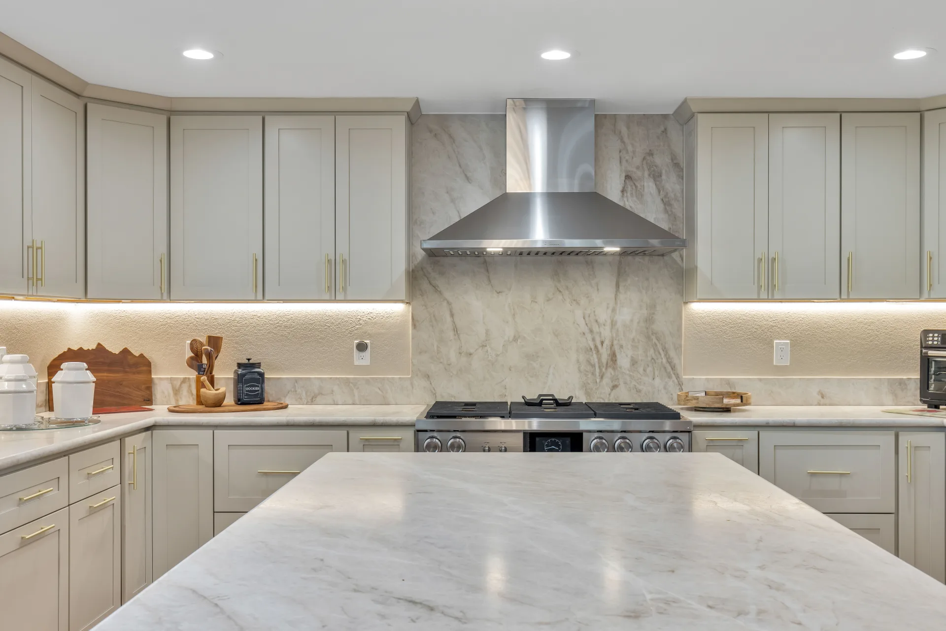 Kitchen remodel in Danville CA — sage green cabinets, marble slab backsplash, custom range hood by Inspired Builders